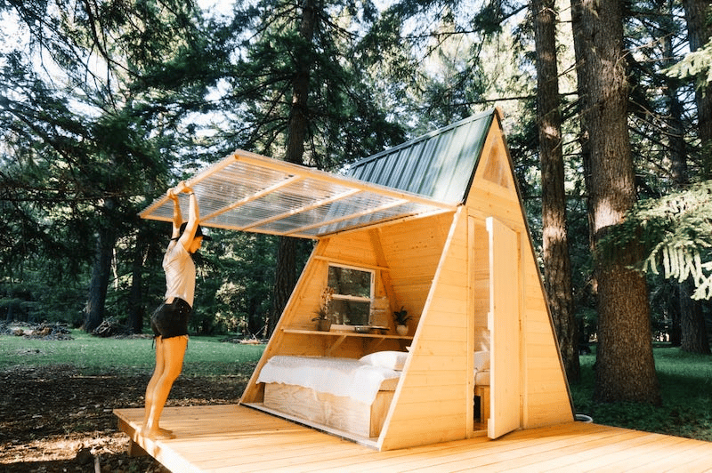 A woman closing the glass panelling on a wooden tent