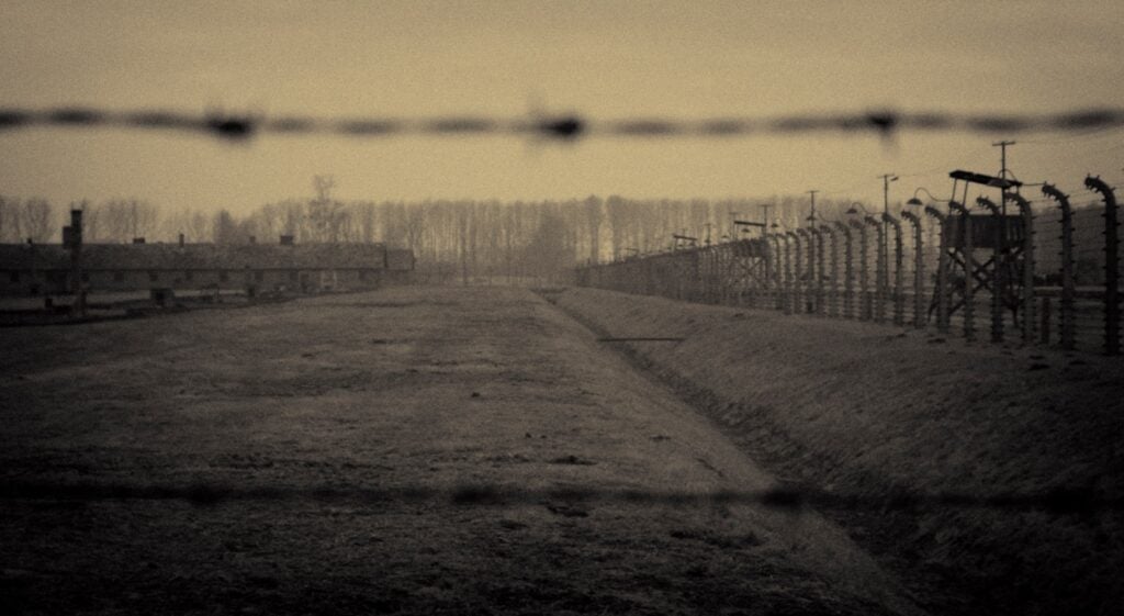 a fenced in area with a dirt road in the foreground