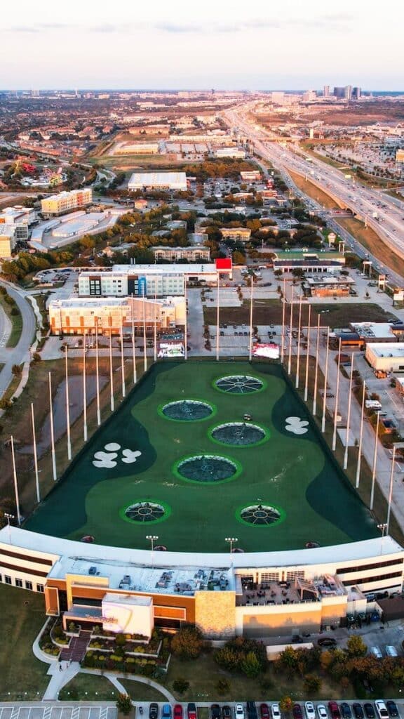 Stunning aerial photo of a modern recreational golf venue during sunset in an urban setting.