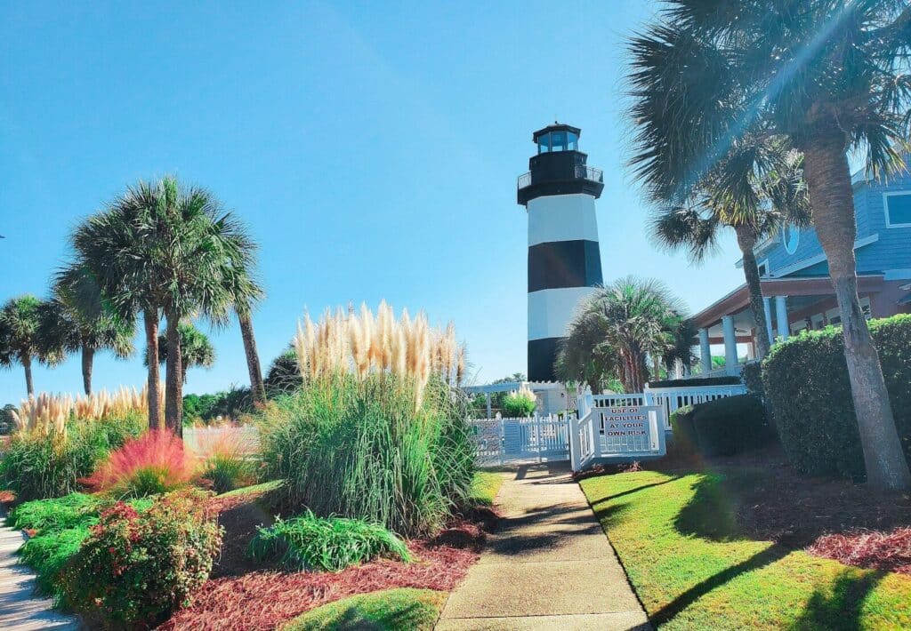 a black and white lighthouse surrounded by palm trees