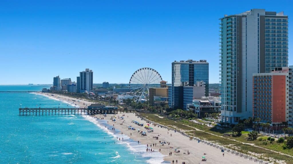 A view of a beach with a ferris wheel in the distance