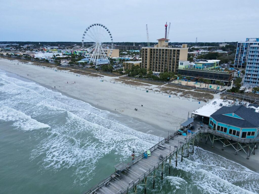 Aerial shot of Myrtle Beach with iconic pier and ferris wheel, capturing coastal beauty.
