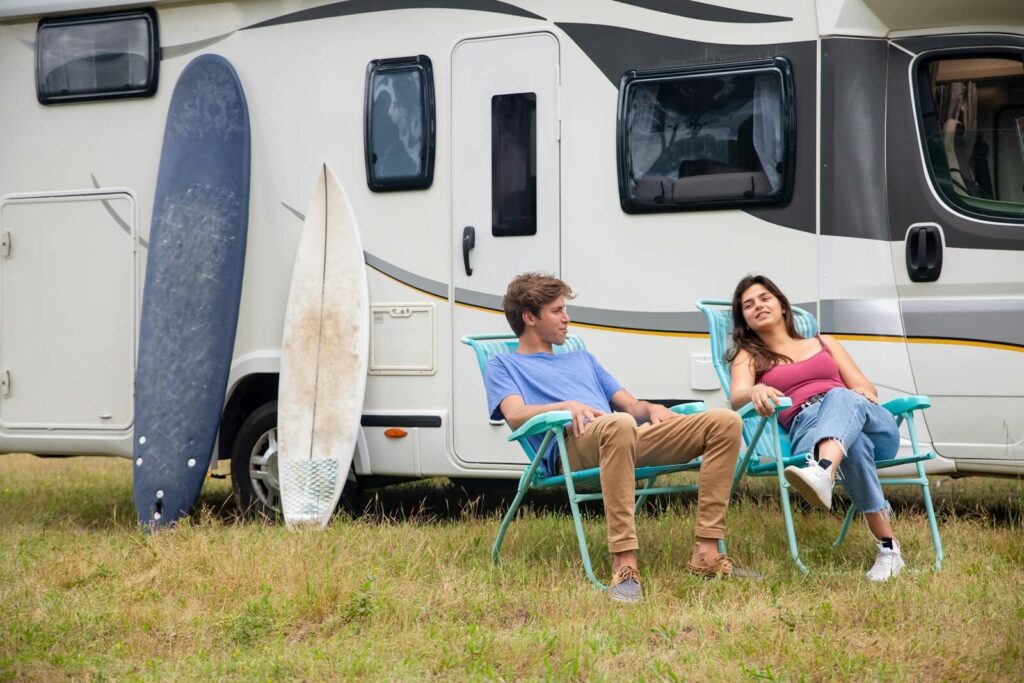 Sun Outdoors Myrtle Beach: Why It Belongs on Your 2026 Vacation Itinerary 12 Couple relaxing by an RV with surfboards on a grass field, enjoying leisure time in Portugal.